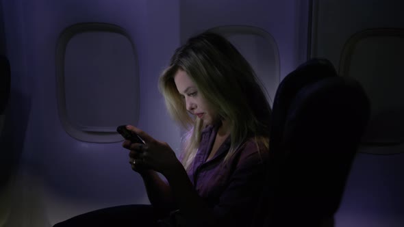Woman using cell phone at night on airplane