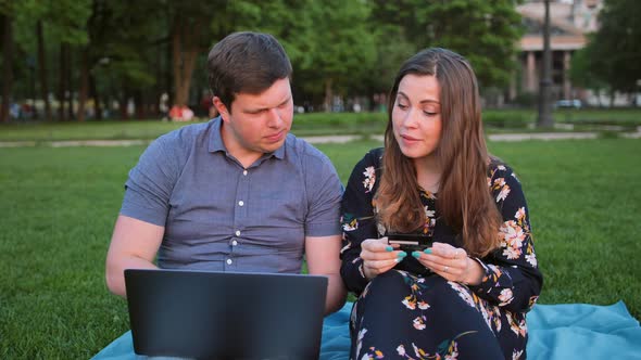 Young Couple Shopping Online Using Laptop and Credit Card alt