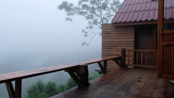 A woman setting a wooden table and chair at the terrace on foggy day