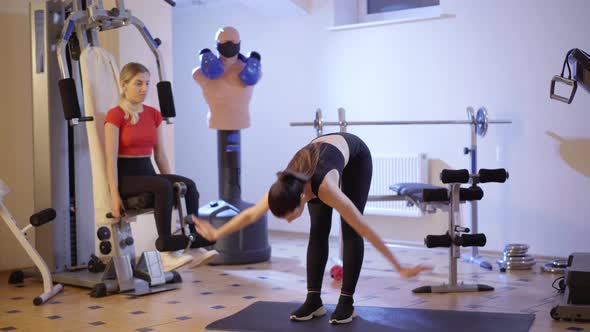 Wide Shot Portrait of Slender Concentrated Sportswoman Bending Forward in Gym with Focused alt