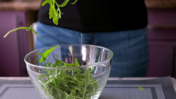 Healthy Lifestyle  Woman Pouring Arugula Into Glass Bowl alt