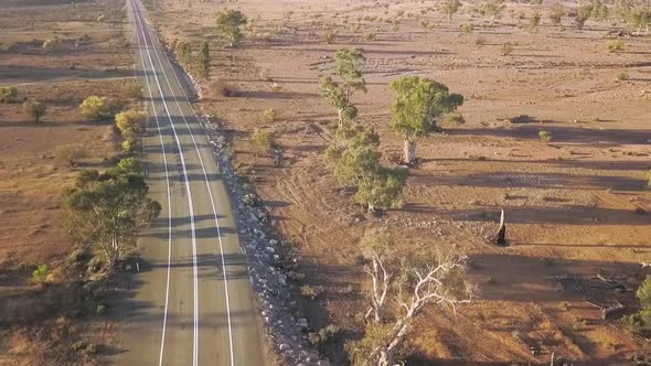 Drone lifting up over road to reveal Australian outback landscape alt