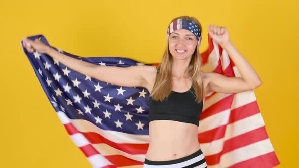 Happy Patriot Girl In Sportswear Holds And Waving American Flag. celebrating Independence Day alt