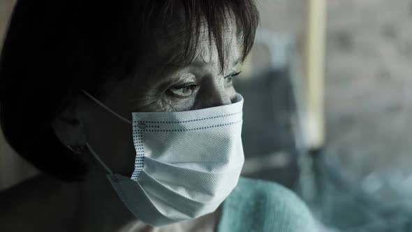 Senior Woman in Face Mask Behind Window on Quarantine alt