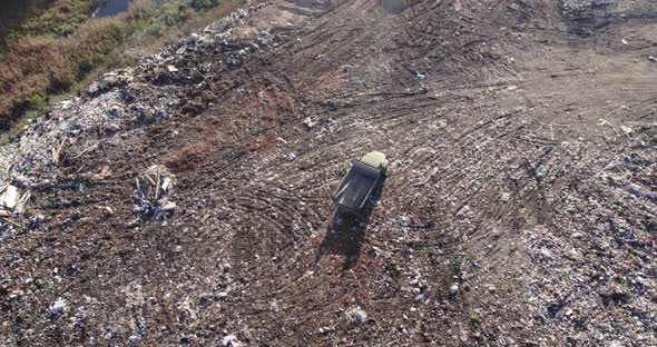 Truck with an Empty Body on a Pile of Waste in a Landfill alt