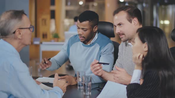 Business Colleagues Discussing Work Sitting at Conference Table in Office. alt