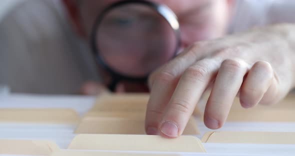 Man Looking for Document in Folders Using Magnifying Glass  Movie Slow Motion
