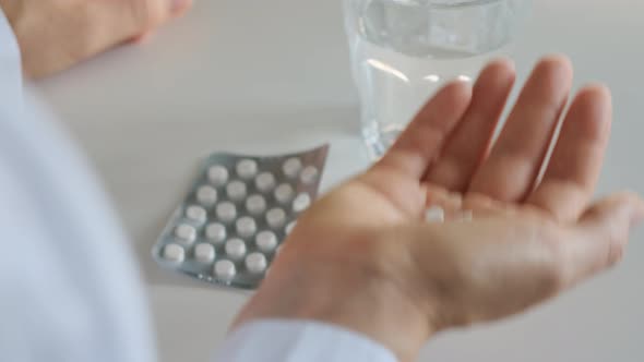 White Small Pills in Hand of the Patient alt