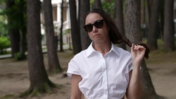 Portrait of Adult Woman in Park Area at Summertime Brunette is Wearing Sunglasses alt