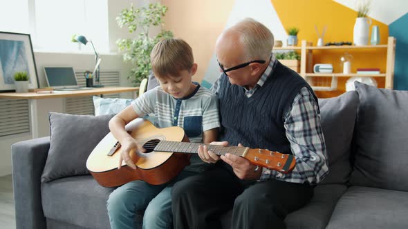 Slow Motion of Cheerful People Grandson and Grandfather Playing the Guitar at Home alt