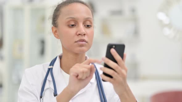 Portrait of Focused Young African Doctor Using Smartphone alt