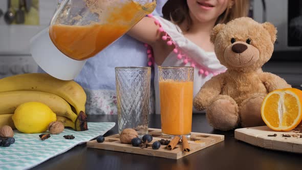 Little Girl with Mom Pouring Smoothie in Glasses alt