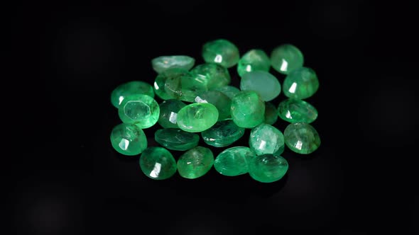 Natural Green Emerald on the Turning Table on the Black Background