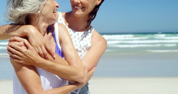 Mother and daughter embracing each other at beach alt