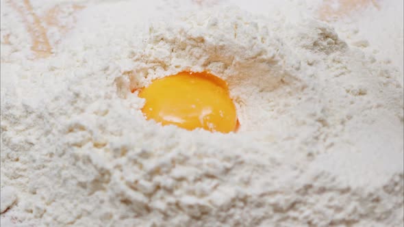 Yolk Falls Into the Flour on a Wooden Table alt