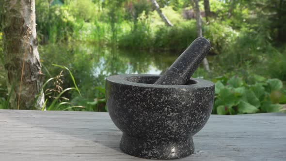 Hand is Putting Salt and Spices Into Grey Stone Mortar in Slow Motion Outdoors alt