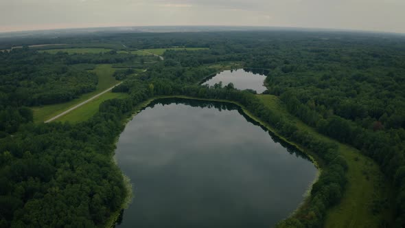 Aerial View of Lakes with Growing Forest Reflection of Sky and Clouds in the Water alt