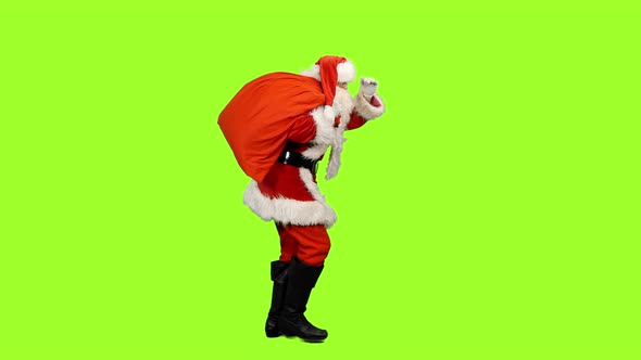 Santa Carrying Christmas Gifts and Looks into Distance on Green Background