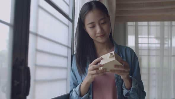 Attractive portrait young Asian woman freelance architect holding a model of home.