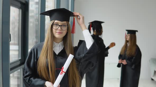 The Graduate Holds a Diploma in One Hand and a Hat in the Other alt