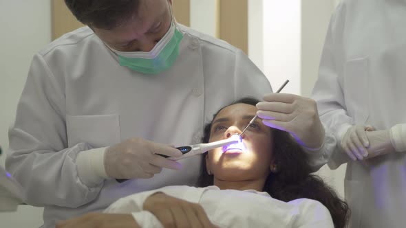 A dentist checking up Latin woman's teeth by using dental mouth mirror at hospital clinic