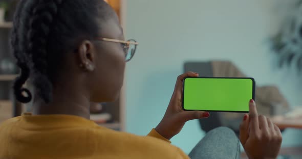 African American Woman Scrolling and Tapping on Green Screen of Mobile alt