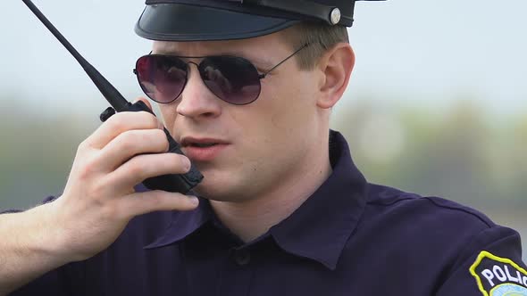 Determined Police Officer Communicating on Walkie-Talkie, Exchanging Information alt