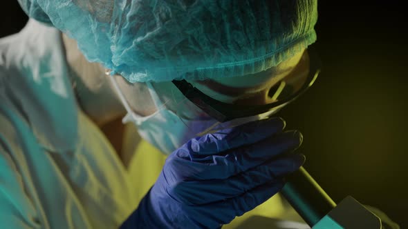 A Woman Scientist is Looking Into Microscope Biochemical Research