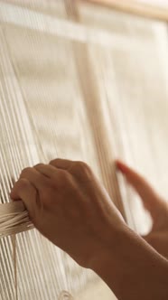 The girl is engaged in weaving at home.