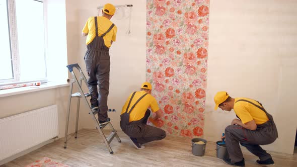 Builders Hang Wallpaper in the Apartment. alt
