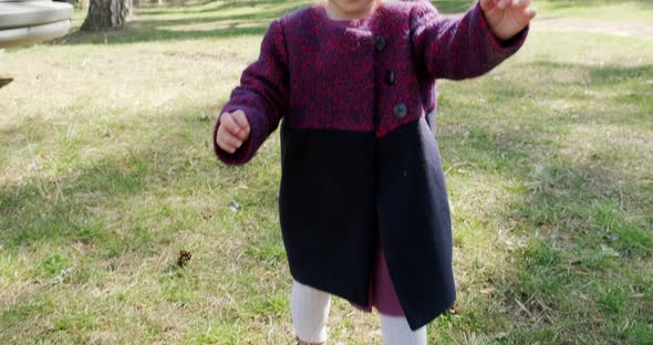 Happy Little Girl Walking in Green Grass Among Trees in Coniferous Forest. Healthy Child Recreation alt