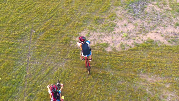 Footage B Roll 4k. Aerial view Drone tracking young People riding a bikes on the meadow