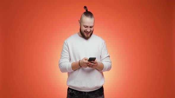 Handsome Bearded Young Brunet Man Is Laughing at What He Saw on Smartphone