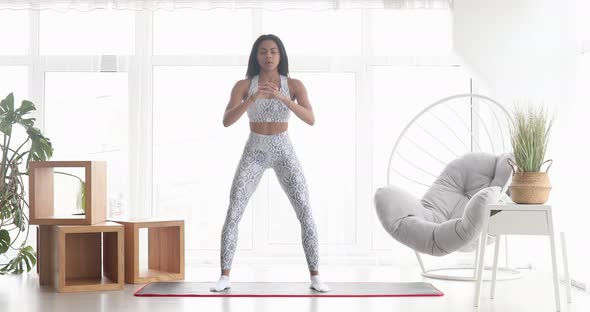 Athletic fit girl doing fitness aerobic exercises for booty in living room. alt