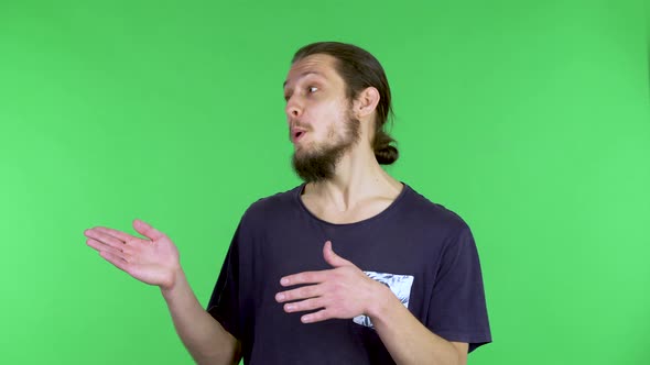 A Darkhaired Man is Talking About Something and with Both Hands is Pointing to Something on the Side alt