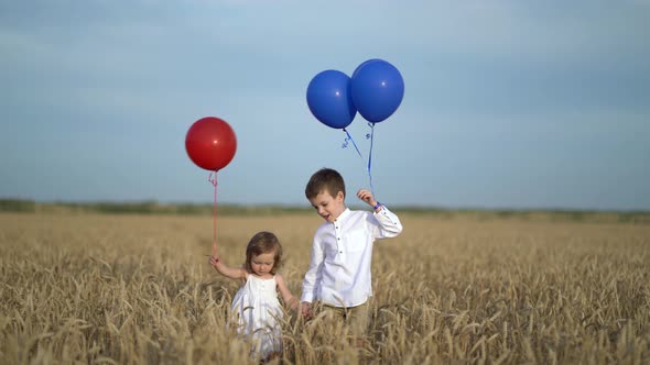 Little Girl and Boy with Balloons Walking Through Wheat Field