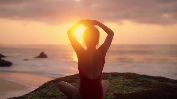 Silhouette of Young Woman Doing Yoga Exercises. Girl in Red Swimsuit Relaxing on the Ocean Coast alt