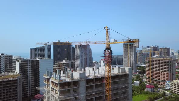 Construction crane on construction site against backdrop of mountains and city. alt