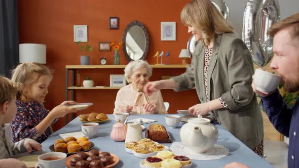 Woman Giving Plates to Family Members on Grandma Birthday Dinner alt