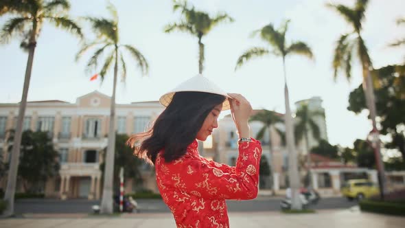 Vietnamese Girl Puts on a National Cap Non La in the Rays of the Evening Sunset in Da Nang alt