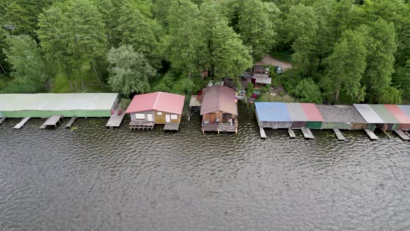 Boat storage along lakeshore of Lake Mirow. Houses And Huts. Drone Shot panning right. alt