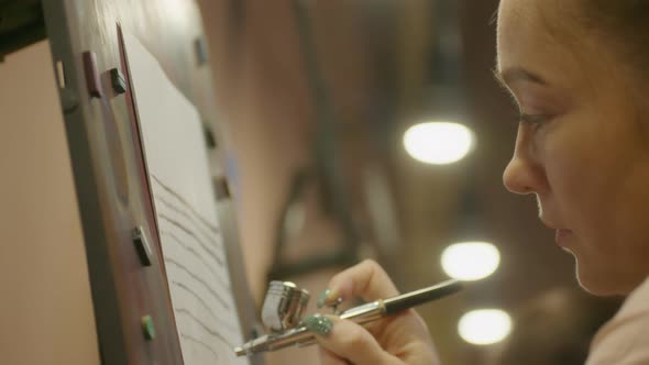 Woman Artist Learns to Paint with Airbrush with Acrylic Dye Paper and Easel alt