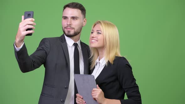 Young Business Couple Using Digital Tablet While Taking Selfie Together