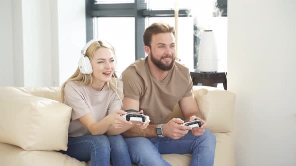 Couple Having Fun While Playing Video Game at Home Holding Joysticks in Hands
