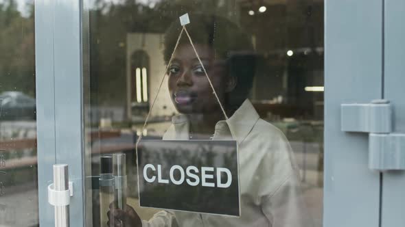 Woman Switching Closed Sign to Open alt