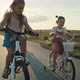 Caucasian family of two elementary age girls on foreground and parents in the background riding bike - VideoHive Item for Sale