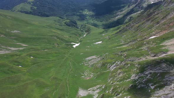 Flying Backward Over a Mountain Valley in Mountains of Adygea on Summer Day. Green Trees and Bushes alt