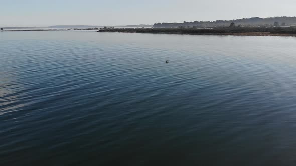 couple on a kayak in the middle of a still lake next to a peninsula