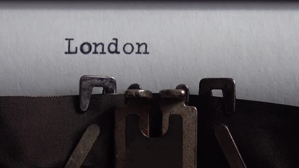 Typing city name London on a vintage typewriter. Close up. alt