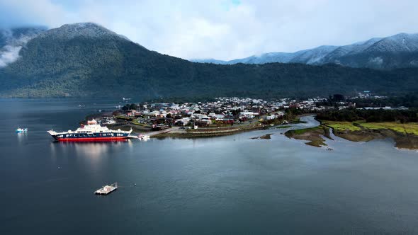 Aerial view truck left of Hornopiren, Chile. Ferry in the small harbor and snow-capped mountains on alt
